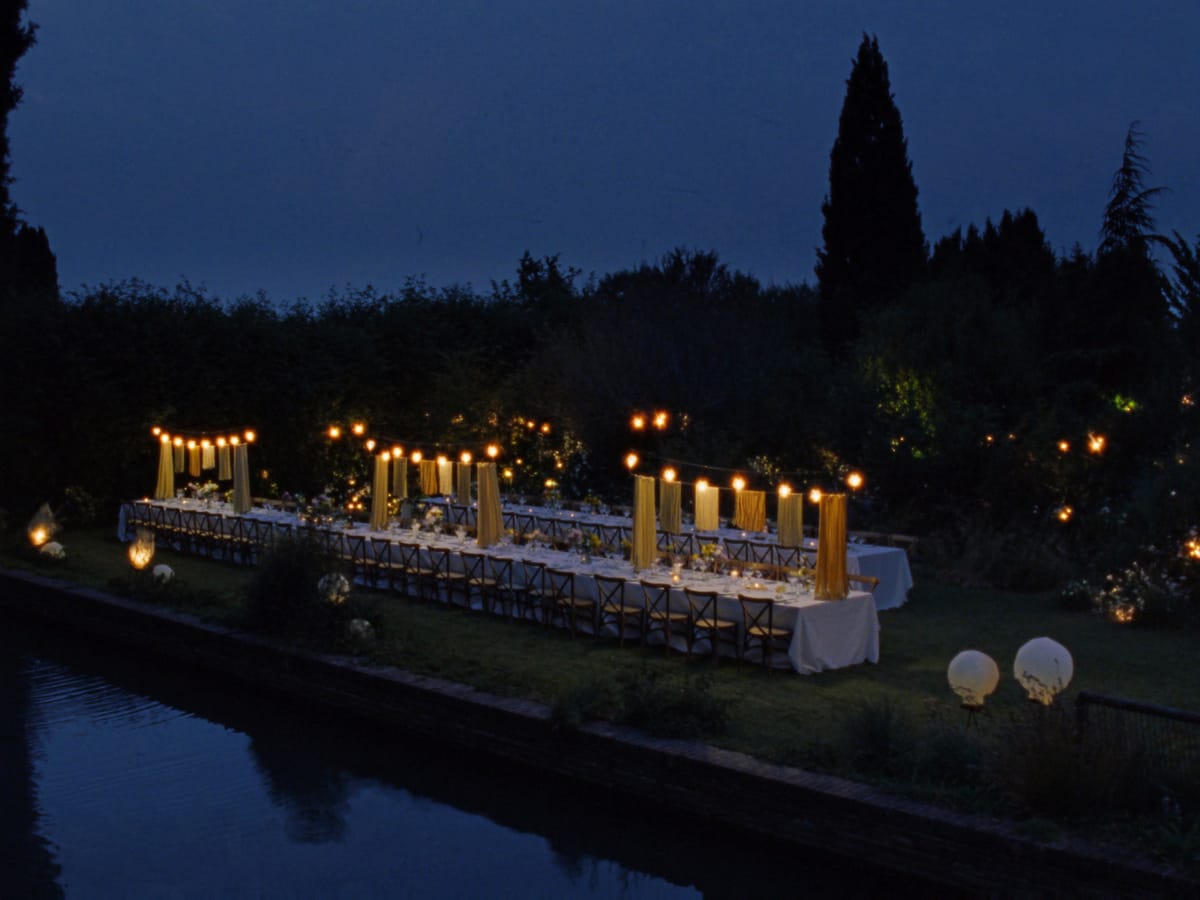 Mesa de festa de casamento sob varal de luzes ao anoitecer