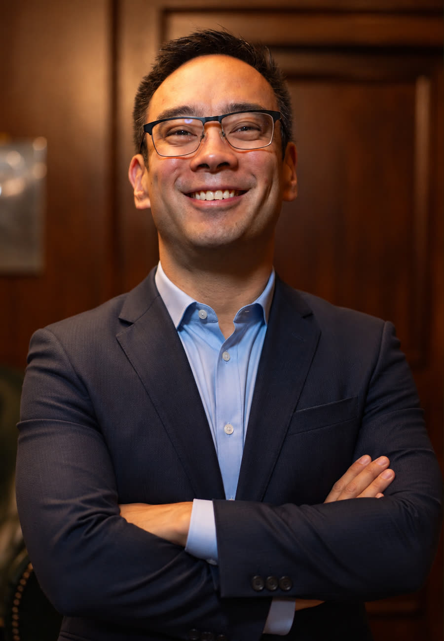 Jônatas Yasumoto, consultor autorizado Ademicon, sorrindo de braços cruzados em um escritório